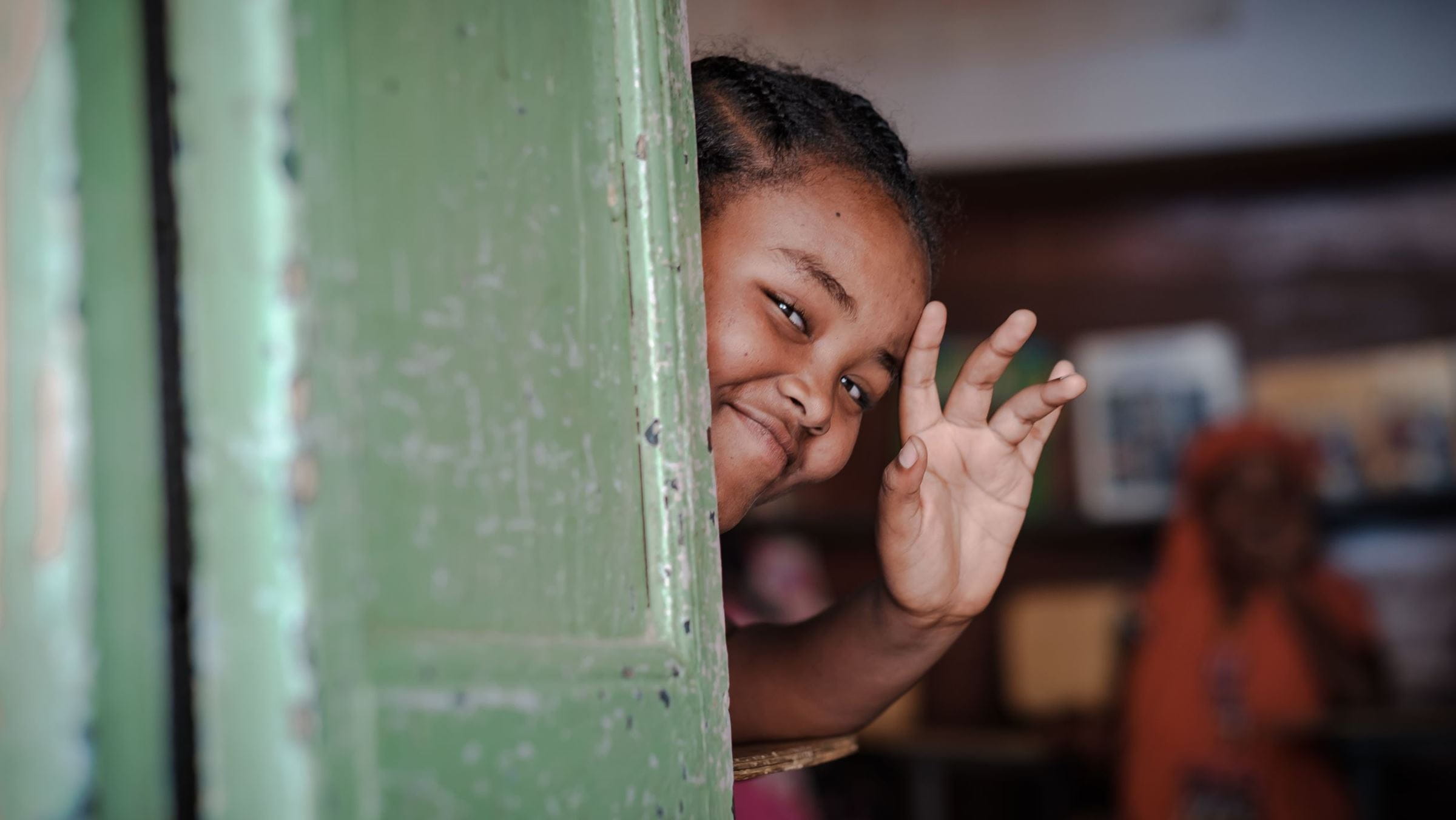Ein äthiopisches Mädchen blickt aus der Haustür und winkt. (Quelle: Jakob Studnar)